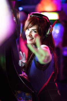 Cosplayer dressed as a futuristic character with headphones, gesturing peace sign in a gaming environment.